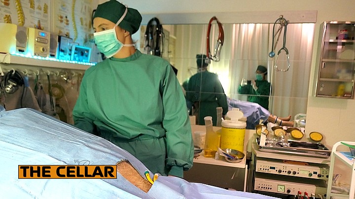 Mrs. Dr. Jill en switch T/takara in de onderzoekskamer van The Cellar Switch T/takara houdt de vinger aan de pols, terwijl Mrs. Dr. Jill fotografeert